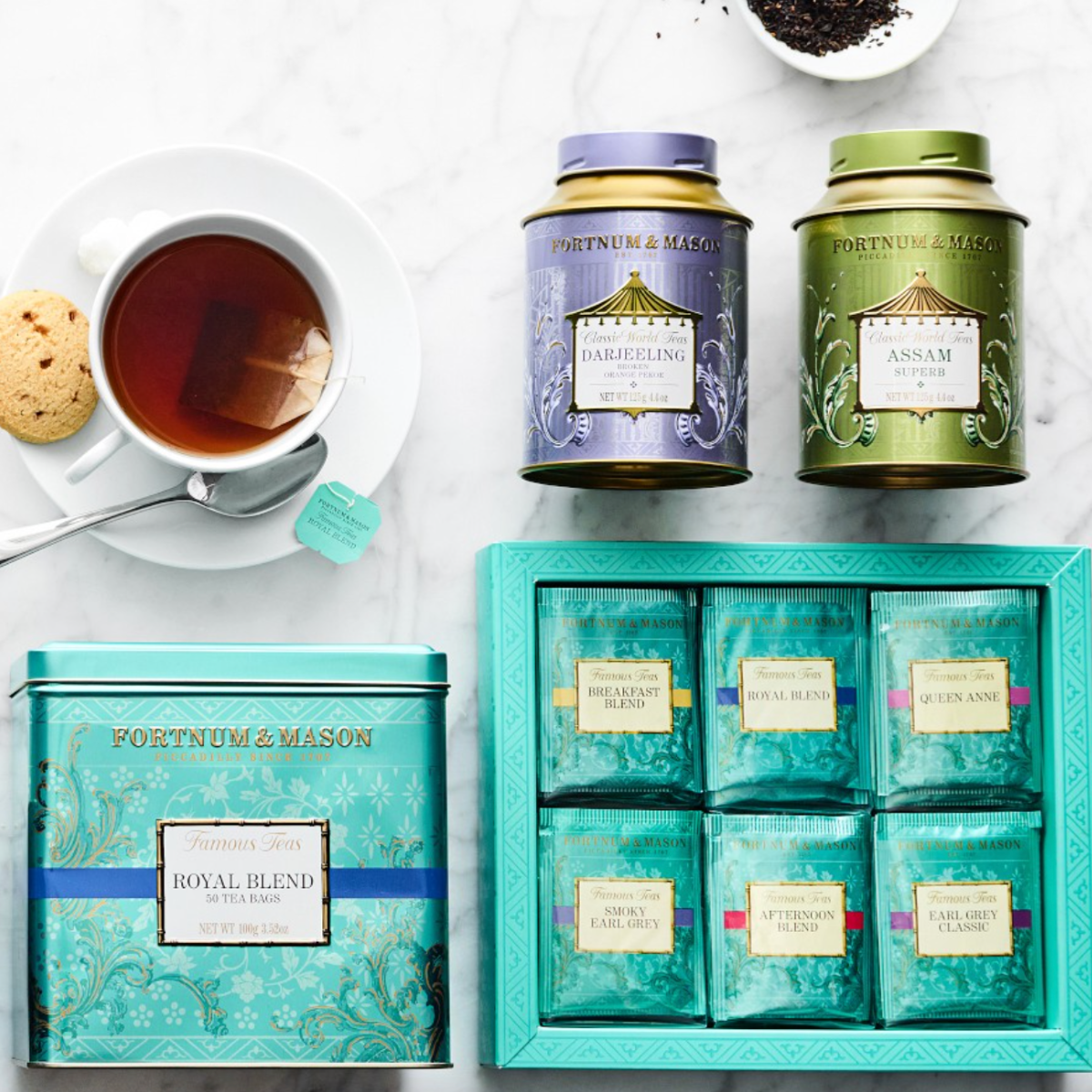 A Fortnum & Mason tea gift set with Royal Blend tea, preserves, and lemon curd biscuits in signature eau-de-nil packaging.