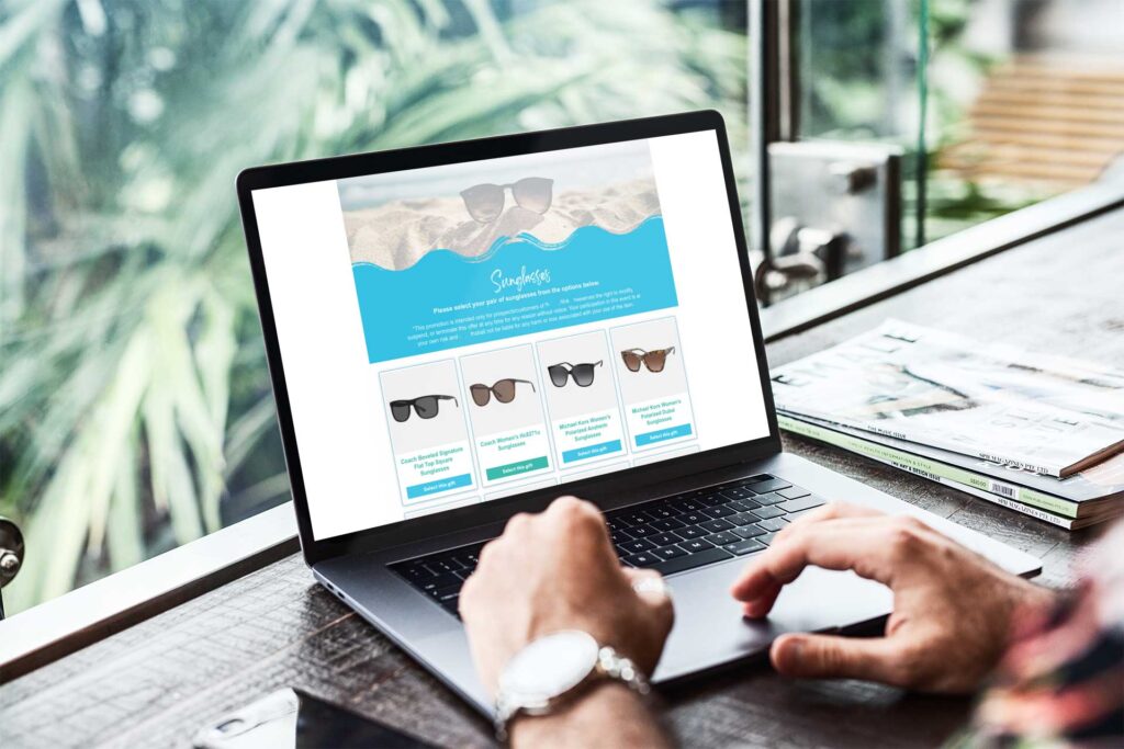 Laptop screen displaying a sunglasses online gifting website with four different styles and a selection form.