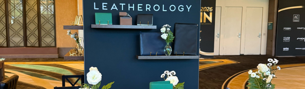 LEATHEROLOGY display features shelves hosting dark leather notebooks, cases, and white flowers.